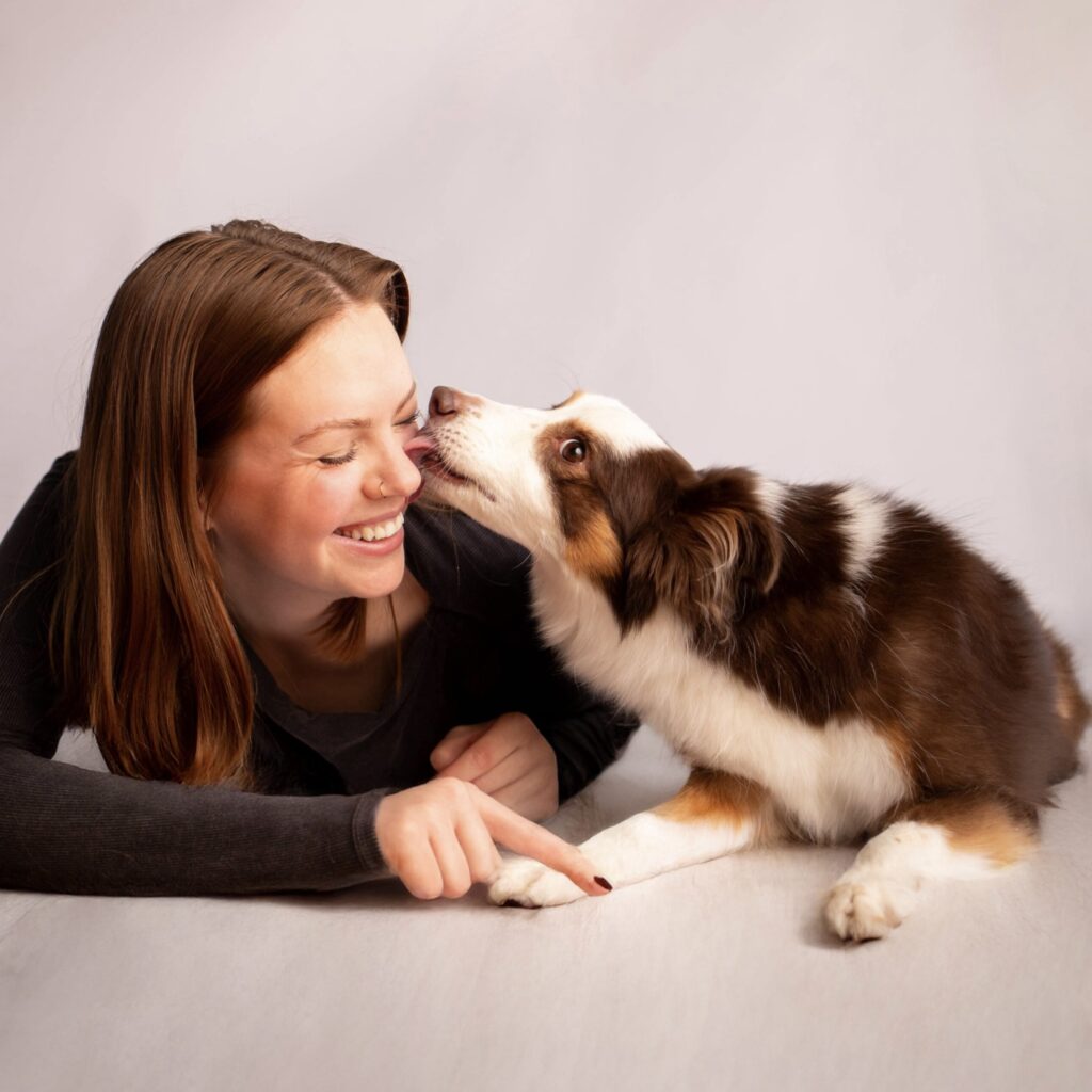 Dog playfully licking woman's face